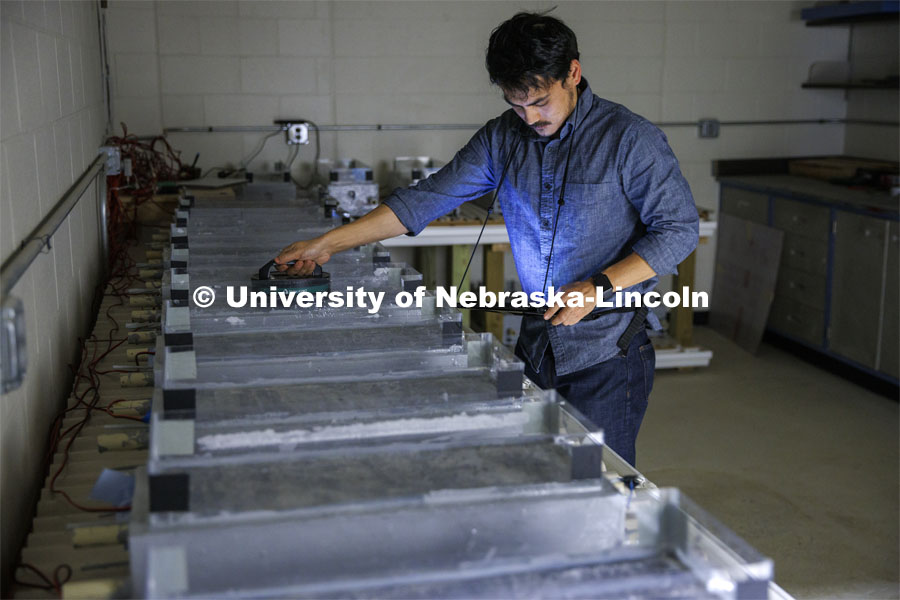 Dipendra Shrestha measures conductivity of a concrete block in Chungwook Sim’s Macrocell Corrosion Testing Setup. An electrical current is measured through a block of concrete being soaked with salt water to see how highways and bridges break down from salt treatments in winter. College of Engineering photo shoot at Peter Kiewit Institute in Omaha. April 5, 2022. Photo by Craig Chandler / University Communication.