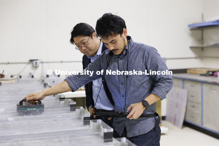 Dipendra Shrestha and Chungwook Sim discuss the conductivity of a concrete blocks in Chungwook Sim’s Macrocell Corrosion Testing Setup. An electrical current is measured through a block of concrete being soaked with salt water to see how highways and bridges break down from salt treatments in winter. College of Engineering photo shoot at Peter Kiewit Institute in Omaha. April 5, 2022. Photo by Craig Chandler / University Communication.