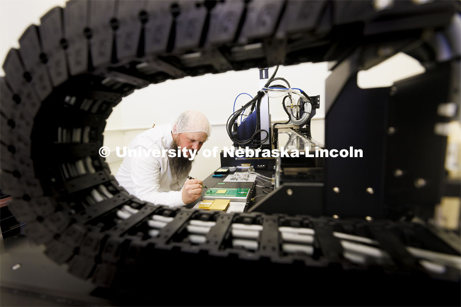 Nebraska’s Caleb Fangmeier, a farm kid from Hebron, stayed up until 2 a.m. as an undergraduate to hear the announcement about the discovery of the Higgs boson. He now holds a doctorate in physics and works as a detector lab manager in Jorgensen Hall. His group is building nearly 2,500 particle detectors that will be used when the Large Hadron Collider restarts sometime between 2024 and 2026. In addition to Caleb, there is one postdoc, three graduate students and five undergraduates who work in the lab. They use gantrys to glue these things together with great precision. April 18, 2022. Photo by Craig Chandler / University Communication.