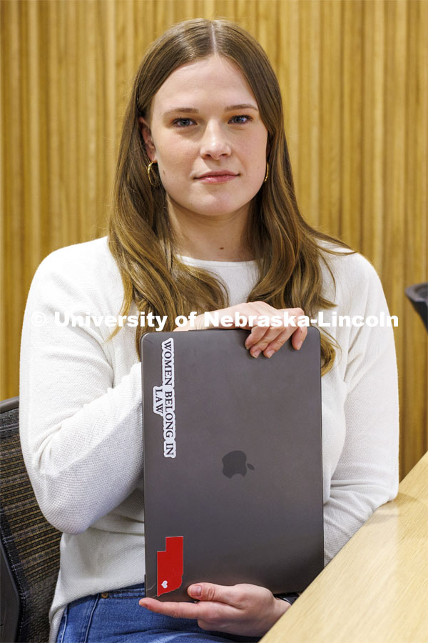 A student shows a sticker on her laptop "Women Belong in Law". College of Law photo shoot. April 20, 2022. Photo by Craig Chandler / University Communication.
