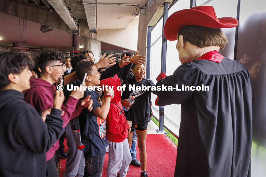 Students from Dawes Middle School in Lincoln meet Herbie Husker during a tour of Memorial Stadium Wednesday given by Dr. Lawrence Chatters, Executive Associate AD for Diversity, Equity and Inclusion. Herbie took time out from a commencement promotional photo shoot to greet his fans. Herbie Husker in cap and gown to promote 2022 spring commencement in Memorial Stadium. May 4, 2022. Photo by Craig Chandler / University Communication.