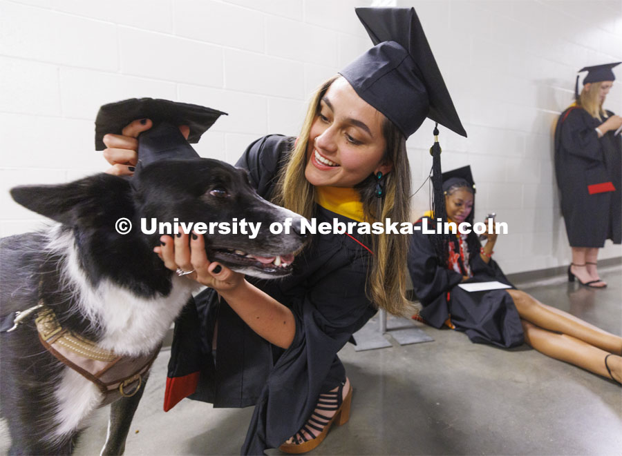 Vilma Maria Montenegro Castro adjusts the mortar board on her service dog, Matty, before the ceremony. Graduate commencement in Pinnacle Bank Arena. May 13, 2022. Photo by Craig Chandler / University Communication.
