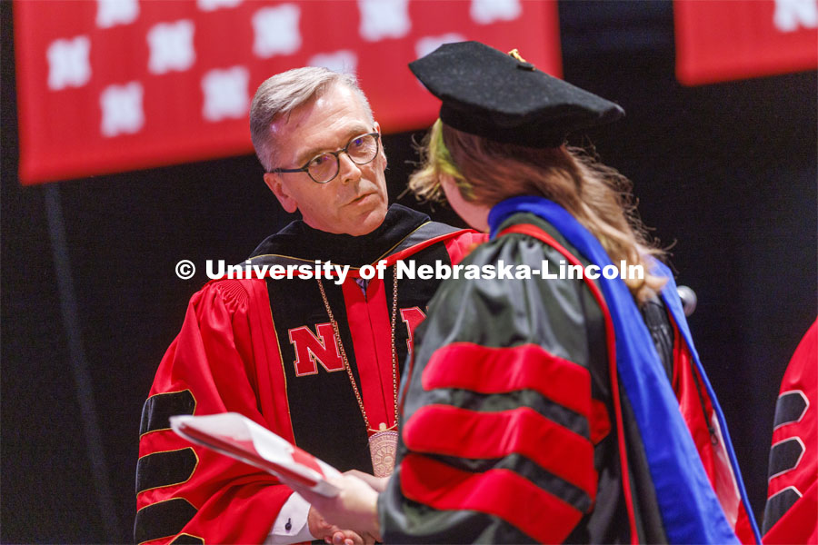 Chancellor Ronnie Green talks with a doctoral degree graduate. He says he enjoys asking each doctoral candidate about their future plans as he hands them their diplomas. Graduate commencement in Pinnacle Bank Arena. May 13, 2022. Photo by Craig Chandler / University Communication.