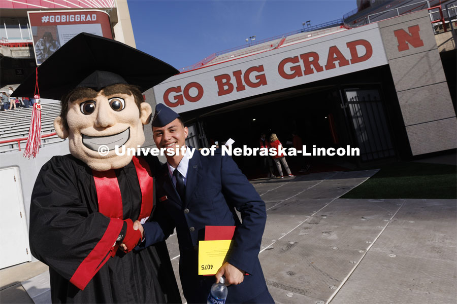 An ROTC student poses with Herbie Husker at the UNL undergraduate commencement in Memorial Stadium. May 14, 2022. Photo by Craig Chandler / University Communication.