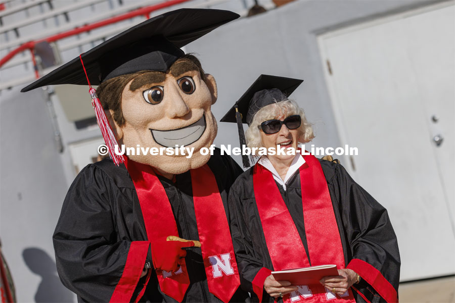 Carol (Dahl Leacox) Livingston takes a photo with Herbie Husker. Livingston finally received her diploma — Bachelor of Science in Business Administration — for her studies at the University of Nebraska-Lincoln from 1955-59. UNL undergraduate commencement in Memorial Stadium. May 14, 2022. Photo by Craig Chandler / University Communication.