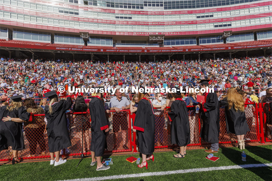 Graduates, friends and family talk at the end of the field before commencement. UNL undergraduate commencement in Memorial Stadium. May 14, 2022. Photo by Craig Chandler / University Communication.