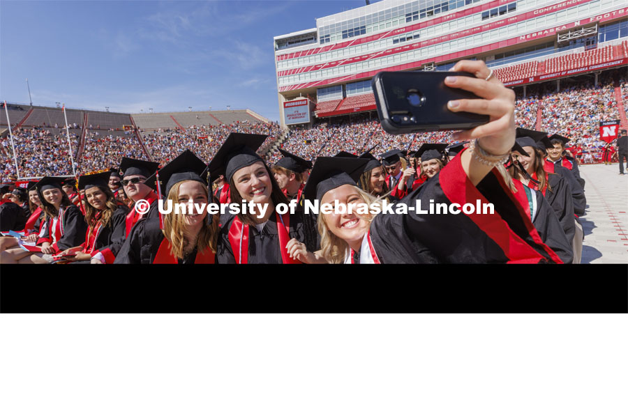 Madalyne Lorenze takes a selfie with her COJMC friends. UNL undergraduate commencement in Memorial Stadium. May 14, 2022. Photo by Craig Chandler / University Communication.