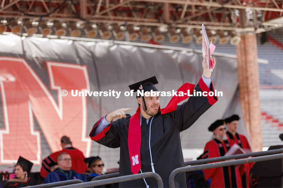 CoJMC graduate Allan Fisher shows off his diploma to family and friends. UNL undergraduate commencement in Memorial Stadium. May 14, 2022. Photo by Craig Chandler / University Communication.
