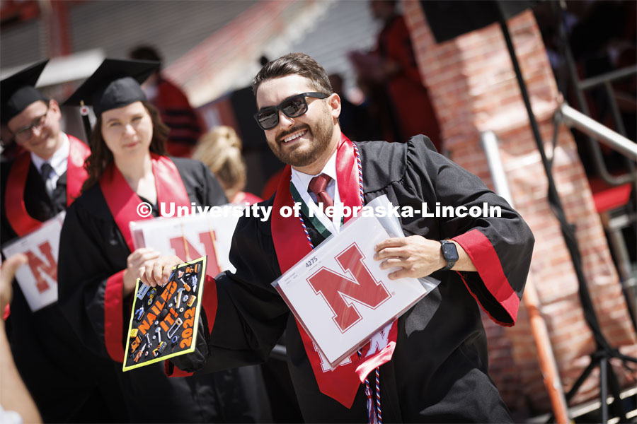 Rodrigo Venegas, First-gen, Marine, non-traditional student, veteran, construction management major, from Grand Island, shows off his decorated mortar board to the graduation photographer. UNL undergraduate commencement in Memorial Stadium.  May 14, 2022.  Photo by Craig Chandler / University Communication.