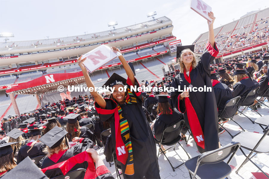 Cherish Perkins and Sydney Petersen wave to her family as they return to her seat after receiving their CEHS diplomas. UNL undergraduate commencement in Memorial Stadium. May 14, 2022. Photo by Craig Chandler / University Communication.