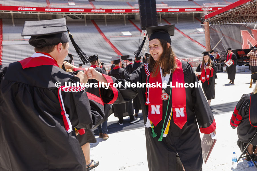 Katelyn Hill high fives a friend after she received her diploma. UNL undergraduate commencement in Memorial Stadium. May 14, 2022. Photo by Craig Chandler / University Communication.