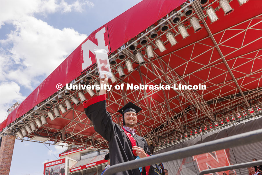 CASNR grad Caden Schuster acknowledges the cheers of everyone as he is the last graduate to walk the stage. UNL undergraduate commencement in Memorial Stadium. May 14, 2022. Photo by Craig Chandler / University Communication.