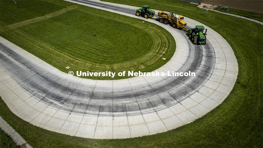 High angle view of a tractor as it pulls the test car (yellow) and an additional tractor for weight as it rounds the test track on east campus. The University of Nebraska Tractor Test Laboratory (NTTL) is the officially designated tractor testing station for the United States. It has operated for more than 100 years. East Campus. May 27, 2022. Photo by Craig Chandler / University Communication.