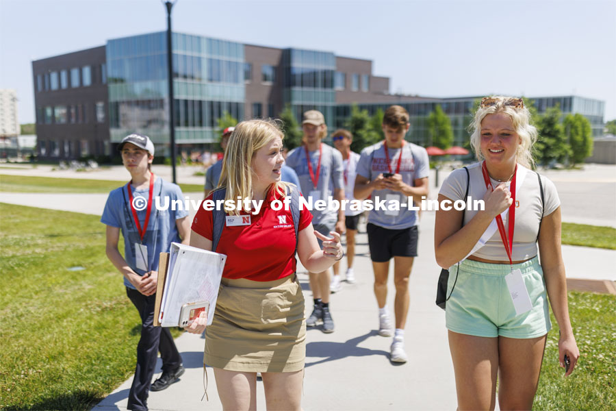 New Student Orientation Leader Malia Bloemker talks with Savanna Musich as they discuss residence halls on campus. NSE Leaders walking on campus with their student groups. June 16, 2022. Photo by Craig Chandler / University Communication.