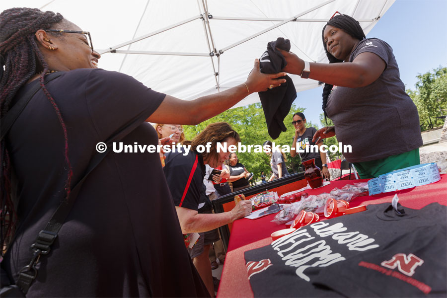 Jerri Harner (right), executive specialist to the vice chancellor for diversity and inclusion, hands out T-shirts from the shade of a canopied table. Juneteenth, the federal holiday that commemorates the emancipation of enslaved Black Americans, is celebrated in an event starting at noon on the Nebraska Union Plaza. June 20, 2022. Photo by Craig Chandler / University Communication.