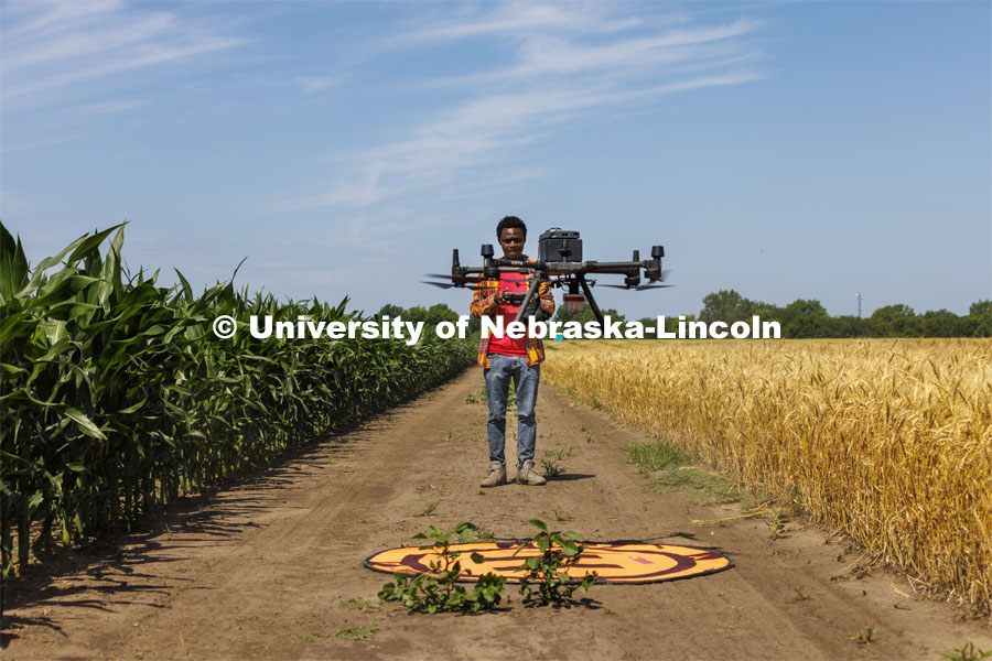 Pascal Izere, master’s student in Biological Systems Engineering, launches an autonomous drone photographing a field of triticale at the research fields at 84th and Havelock. Biological Systems Engineering fieldwork with drones for phenotyping fields. June 27, 2022. Photo by Craig Chandler / University Communication.