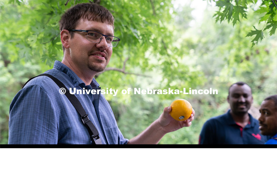 Professor Derek Heeren holds up an orange during his Irrigation Laboratory and Field Course class trip to Salt Creek at Wilderness Park. July 8, 2022. Photo by Jordan Opp for University Communication.