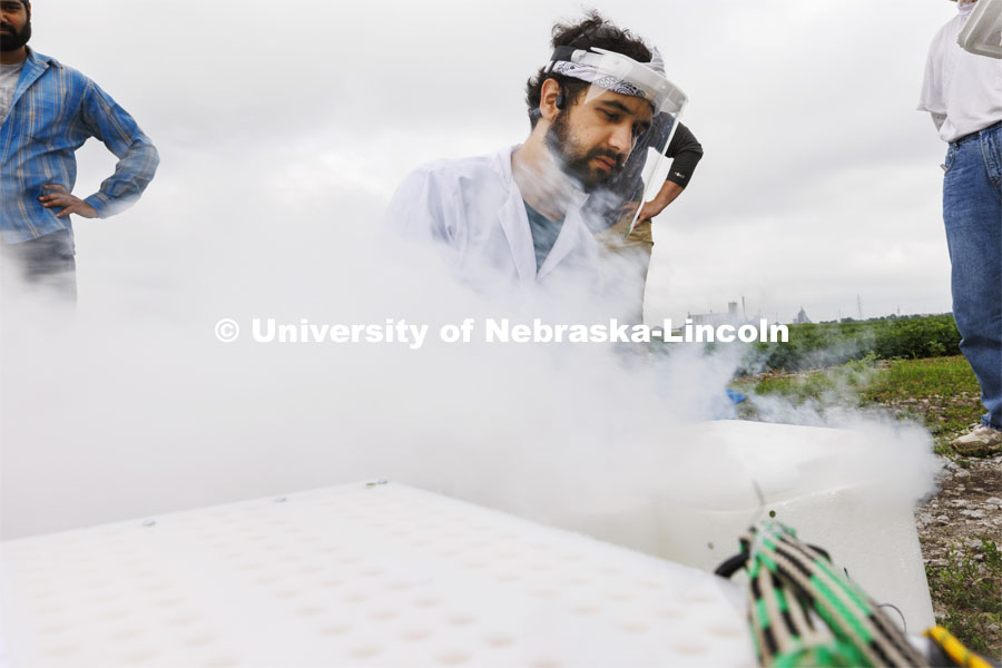 Jon Turkus makes a fog as he combines dry ice from several portable field kits while field phenotyping corn plant DNA in James Schnable’s field northeast of 84th and Havelock. July 8, 2022. Photo by Craig Chandler / University Communication.