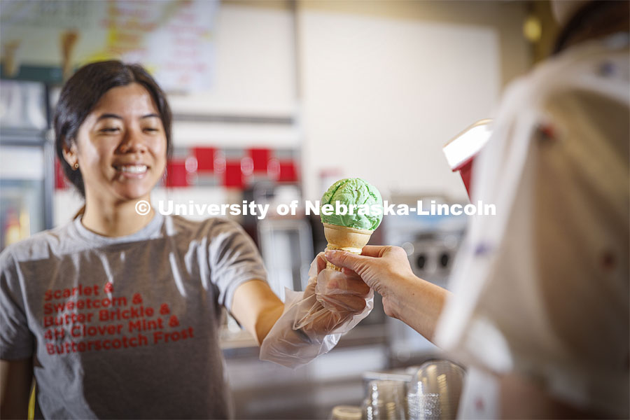 Vi Tran, a senior in actuary science, serves up a cone of Clover 4-H Mint. Ice cream is scooped up at the Dairy Store on East Campus. July 18, 2022. Photo by Craig Chandler / University Communication.