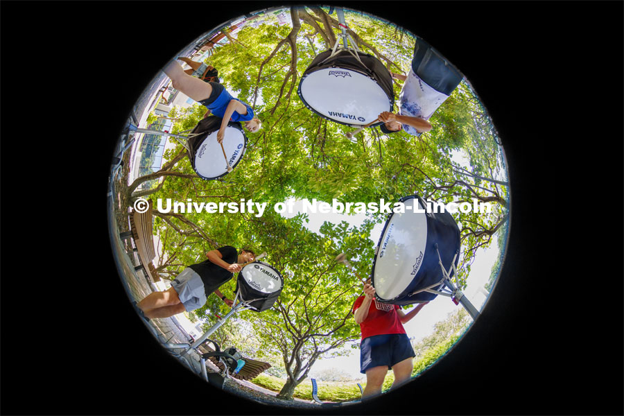 The Cornhusker Marching Band percussion groups kick off the school year. Bass drummers, clockwise from lower left, Carter Ross, Abby Reasoner, Peyton Comer and Alaric Schiltz, practice in the shade outside the Lied Center. Drum line practice on the first day of Cornhusker Marching Band camp. August 11, 2022. Photo by Craig Chandler / University Communication.
