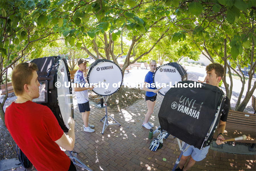 The Cornhusker Marching Band percussion groups kick off the school year. Bass drummers, from left, Alaric Schiltz, Peyton Comer, Abby Reasoner and Carter Ross practice in the shade outside the Lied Center. Drum line practice on the first day of Cornhusker Marching Band camp. August 11, 2022. Photo by Craig Chandler / University Communication.