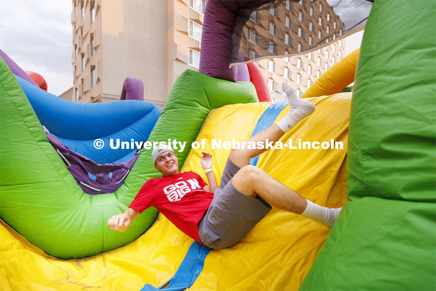 Derek Pirak, a freshman from South Dakota, tumbles through the inflatable obstacle course at the Harper Schramm Smith residence halls block party. August 18, 2022. Photo by Craig Chandler / University Communication.