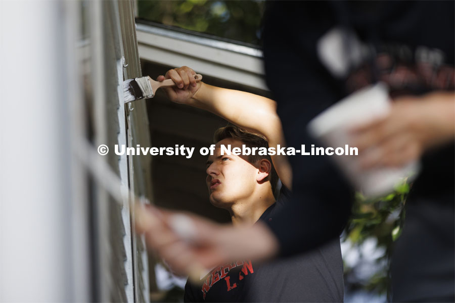 First-year law student Jackson Billings from Omaha concentrates on painting the window trim. First-year law students, faculty, staff and family members come together to paint a house at 518 S. 26th Street. Photo by Craig Chandler / University Communication.