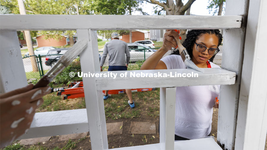 First-year law student Tatiana Eskridge from Omaha paints the porch trim. First-year law students, faculty, staff and family members come together to paint a house at 518 S. 26th Street. Photo by Craig Chandler / University Communication.