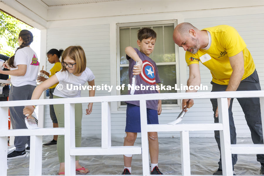 New faculty member Paul Weitzel, teams up with his kids, Jude, center and Amelia to paint the porch trim. First-year law students, faculty, staff and family members come together to paint a house at 518 S. 26th Street. Photo by Craig Chandler / University Communication.