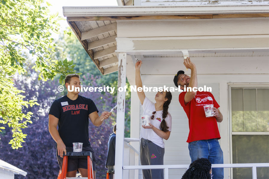 First-year law students Jackson Billings from Omaha, Milla Bevens from Salem, Oregon, and Peter Liffrig from Bismarck North Dakota team up to paint the porch trim. First-year law students, faculty, staff and family members come together to paint a house at 518 S. 26th Street. Photo by Craig Chandler / University Communication.