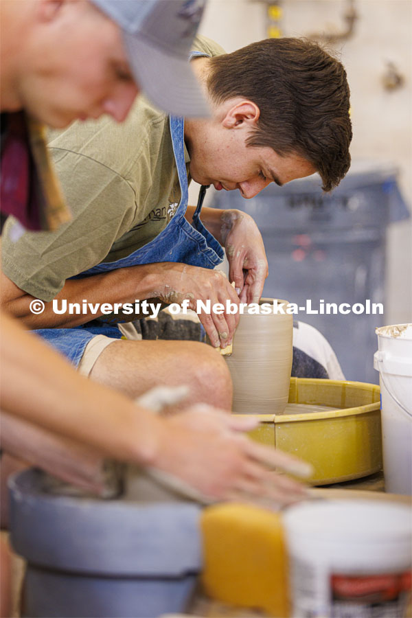Charlie Floeder, a senior from St. Paul, Minnesota, makes a cylinder during a wheel throwing class in Richards Hall. Students in wheel throwing ceramics class. August 24, 2022. Photo by Craig Chandler / University Communication.