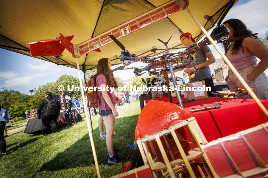 Hayley Hogan, a freshman mechanical engineering student from Lincoln, checks out he drones displayed in one of the engineering club booths. Club Fair in the green space by the Nebraska Union at City Campus. More than 120 recognized student organizations (RSOs) to join for social, professional and leadership interests. RSO members and officers will be on hand to provide details about their organization and answer questions from prospective new members.  August 24, 2022. Photo by Craig Chandler / University Communication.