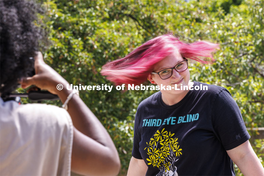 Micaela Coon, a sophomore from Whitehouse, Texas, spins her hair for Ella Gbetanou, a junior from Omaha, during the slow shutter speed lesson during their PHOT 161 - Photography for Non-majors course. The class was doing a photo assignment in the Sheldon Sculpture Garden. August 24, 2022. Photo by Craig Chandler / University Communication.