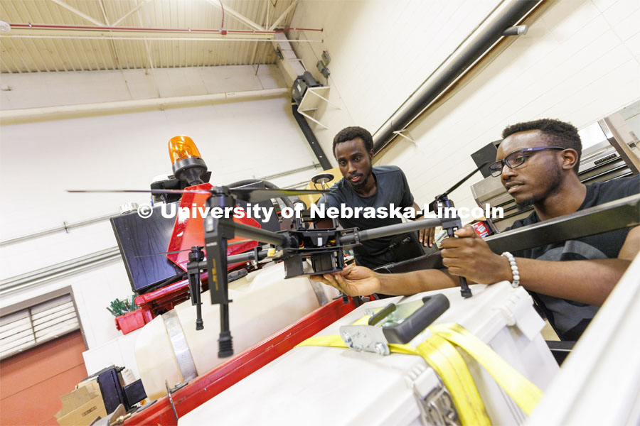 Herve Mwunguzi and Terence Irumva discuss how a drone will be fitted to a robotic tractor to refill seed for planting. Santosh Pitla in his robotics lab on East Campus. September 2, 2022. Photo by Craig Chandler / University Communication.