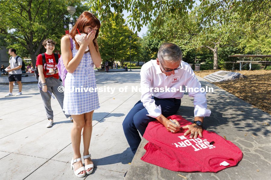Zoelynne Engel, a freshman from Omaha, reacts as Chancellor Ronnie Green autographs her shirt. Chancellor Ronnie Green hands out Grit and Glory t-shirts at the Nebraska Union Plaza. September 7, 2022. Photo by Craig Chandler / University Communication.