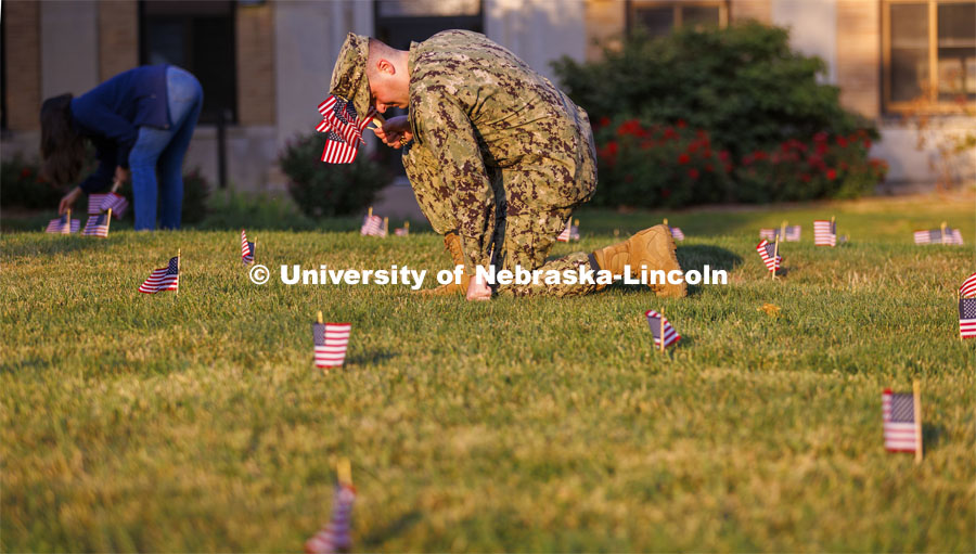 Navy Ensign Drew Merritt places a flag on the East Campus grass. Ens. Merritt is part of the navy ROTC cadre and is a Nebraska graduate. The Nebraska Military and Veteran Success Center, ASUN and others placed flags and signs on East Campus today to commemorate 9/11. The display will be moved to city campus on Monday. September 9, 2022. Photo by Craig Chandler / University Communication.