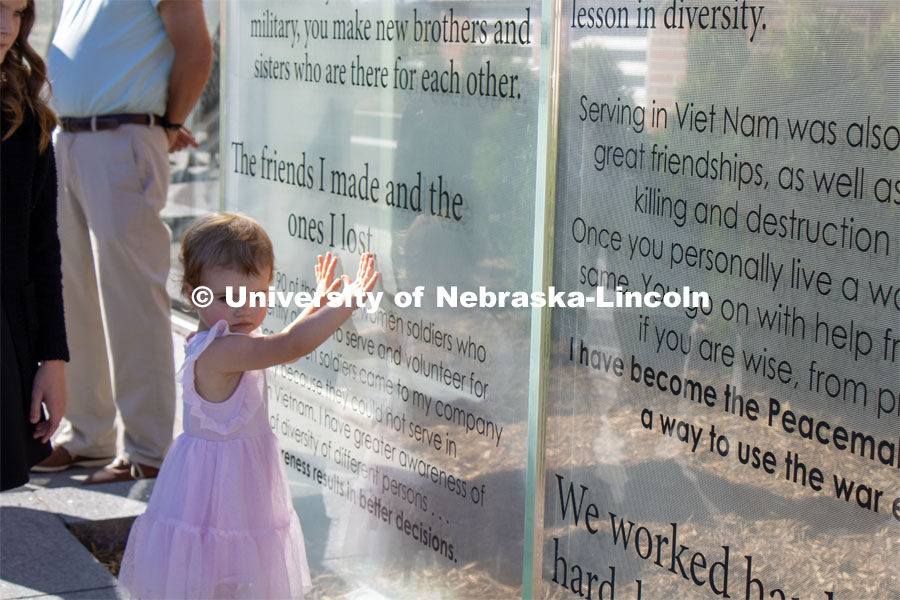 A young girl touches one of the glass panels of the new Veterans’ Tribute. Veteran's Memorial Ceremony. Dedication of Veterans’ Tribute project outside Military and Naval Science building. September 11, 2022. Photo by Gus Kathol for University Communication.
