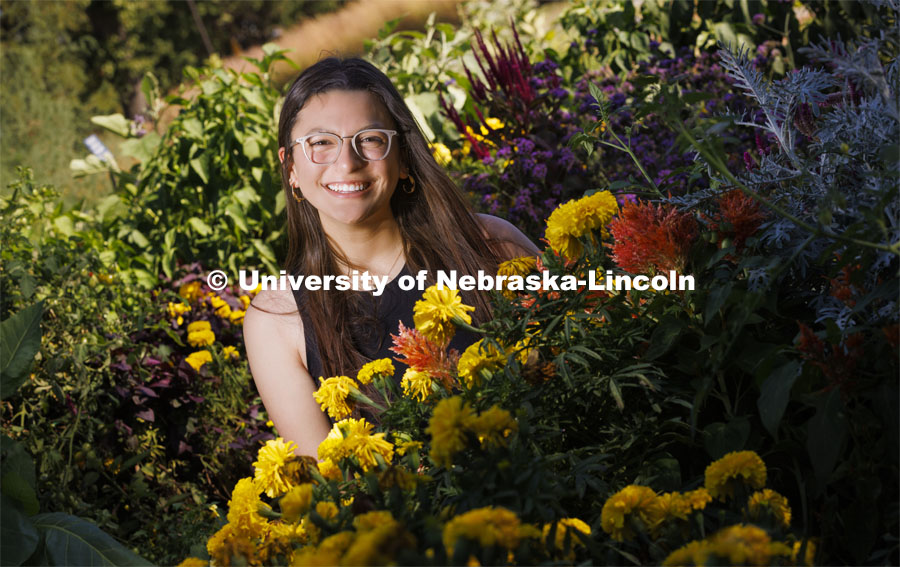 Isabella Villanueva smiles for a photo surrounded by flowers on East Campus. Villanueva is a sophomore fisheries and wildlife major and involved in MASA, CASNR Emerging Leaders in Diversity and MANRRS. She is working to coordinate a fundraiser to help plant native and pollinator plants in the community. September 20, 2022. Photo by Craig Chandler / University Communication.