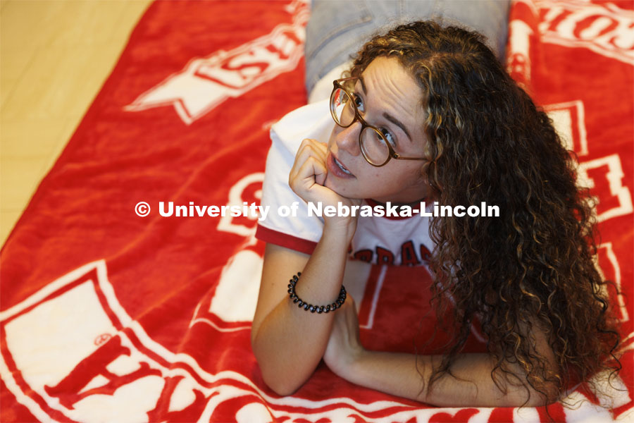 A student lays on the floor on her University of Nebraska blanket. Housing Photo Shoot in Able Sandoz Residence Hall. September 27, 2022. Photo by Craig Chandler / University Communication.