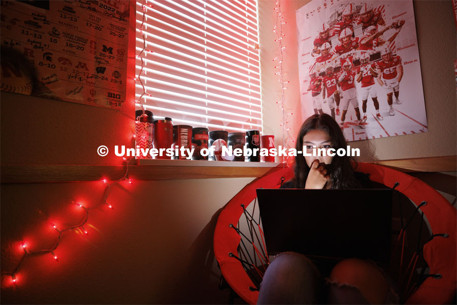A student studies by the glow of red christmas lights in their University Suites Residence Hall room. Housing Photo Shoot in University Suites Residence Hall. September 27, 2022. Photo by Craig Chandler / University Communication.