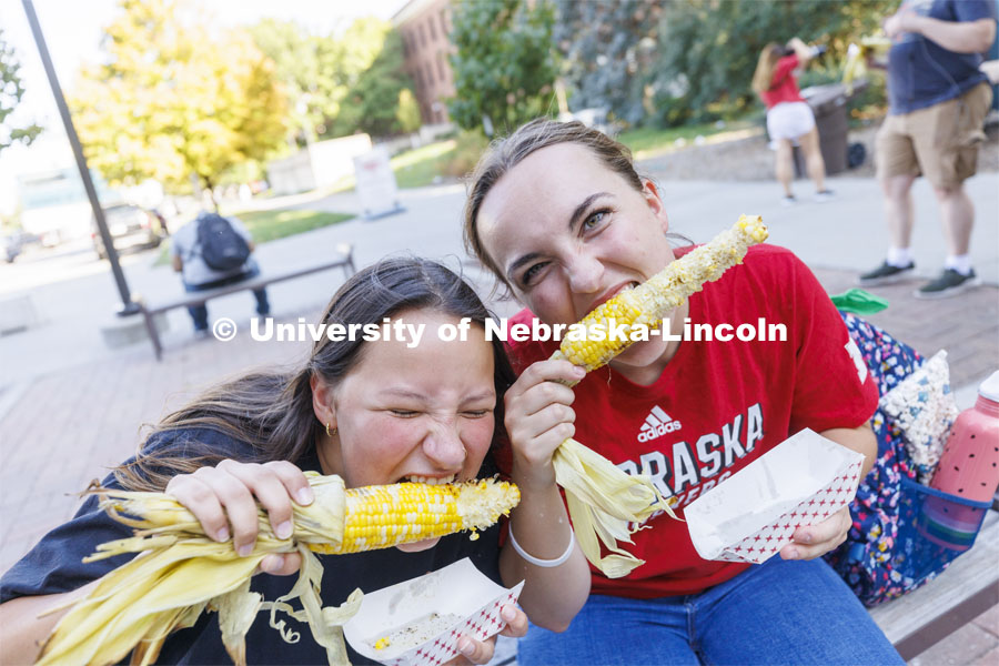Malayna Wingert and Sophie Frappier dig into their ears of corn at Cornstalk. Homecoming Parade and Cornstalk. September 30, 2022. Photo by Craig Chandler / University Communication.