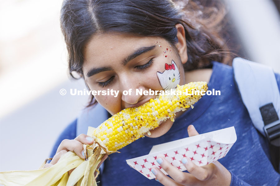 Jina Bagheri eats her corn while sporting a Hello Kitty face painting. Homecoming Parade and Cornstalk. September 30, 2022. Photo by Craig Chandler / University Communication.