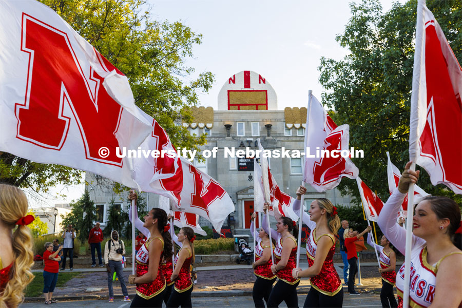 The Cornhusker Marching Band color guard has a super fan peeking out above the Alpha Tau Omega house. Homecoming Parade and Cornstalk. September 30, 2022. Photo by Craig Chandler / University Communication.