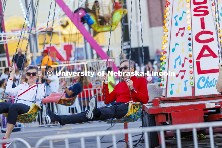 UNL Chancellor Ronnie Green and Husker Jane, his wife, take a spin on the Musical Chairs amusement ride at Cornstalk. Homecoming Parade and Cornstalk. September 30, 2022. Photo by Craig Chandler / University Communication.