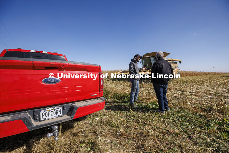 Norm Krug talks with farm manager and grower Andrew McHargue as they wait for the popcorn to get to the proper moisture content before harvesting. Krug, a Nebraska alumnus, drives a red pickup with a personalized tag. Preferred Popcorn grows popcorn near Chapman, Nebraska and throughout the area. It is headed by Norm Krug. October 13, 2022. Photo by Craig Chandler / University Communication.
