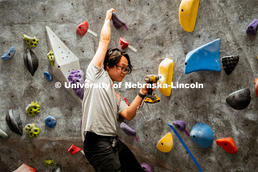 Phung Hong, senior student worker, securing a hold during the League of Extraordinary Boulderers. League of Extraordinary Boulderers scale the climbing wall at Campus Recreation’s Outdoor Adventure Center. November 3, 2022. Photo by Jonah Tran / University Communication.