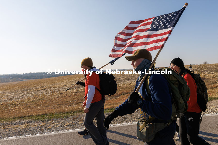 Midshipman Cohan Bonow and Ruck Marchers walk along Holdrege Street in eastern Lancaster County. Nebraska students and veterans march from Memorial Stadium Wednesday morning. "The Things They Carry" ruck march involving military and veteran students from Iowa and Nebraska. To raise awareness about veteran suicide, through the week, the students walk in 20-mile shifts carrying 20-pound backpacks to commemorate the estimated 20 veterans who die by suicide each day. November 15, 2022. Photo by Craig Chandler / University Communication.