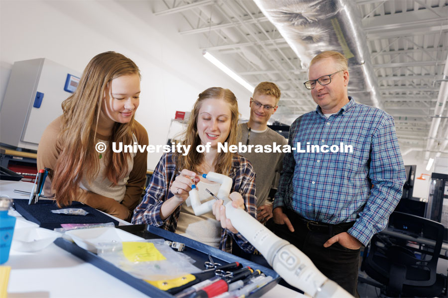 Rachael Wagner explains a robotic surgery device to undergrads Victoria Nelson, left, and David Ryan, center as Shane Farritor listens in. November 29, 2022. Photo by Craig Chandler / University Communication.