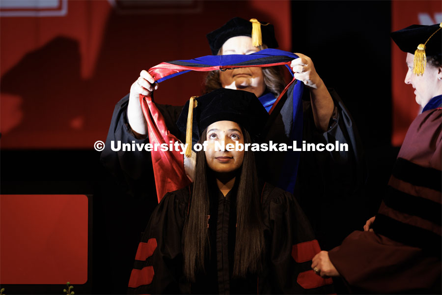 Siya Kunde receives her hood. Graduate Commencement in Pinnacle Bank Arena. December 16, 2022. Photo by Craig Chandler / University Communication.