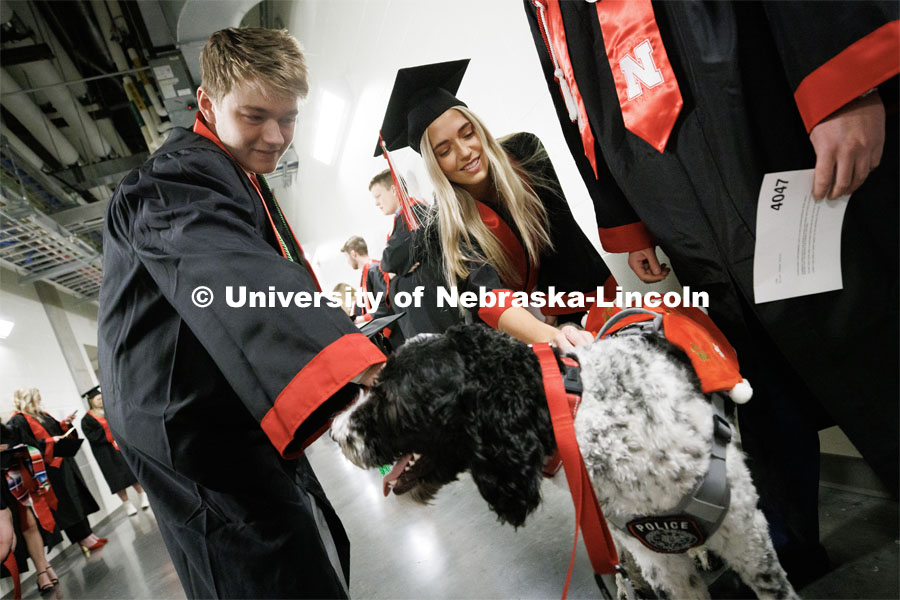 Grads pet Cash the K-9 police dog before the commencement ceremony. Winter Undergraduate Commencement in Pinnacle Bank Arena. December 17, 2022. Photo by Craig Chandler / University Communication.